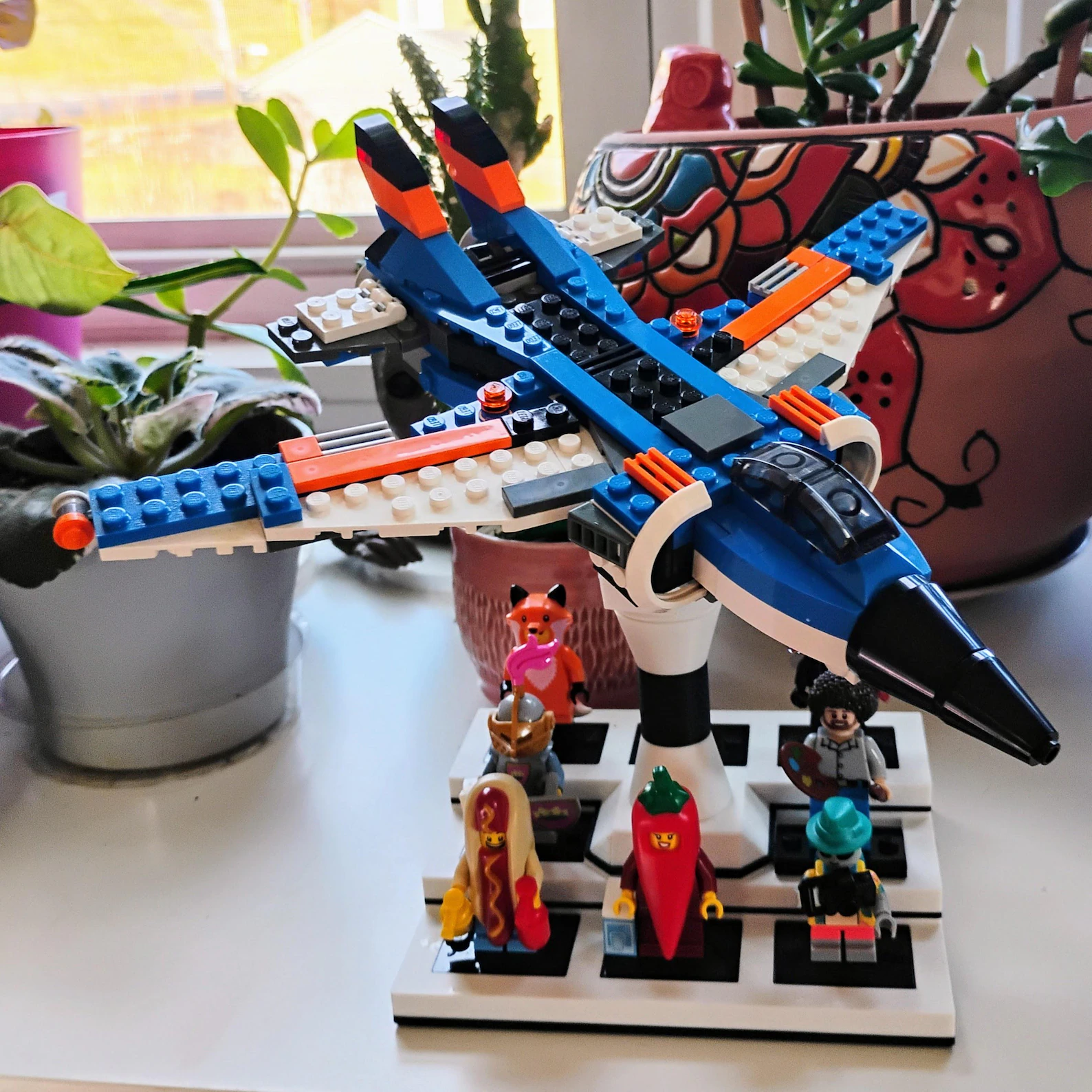 Minifig display with ship stand shown in a real desk setup with a mounted ship and figures below.